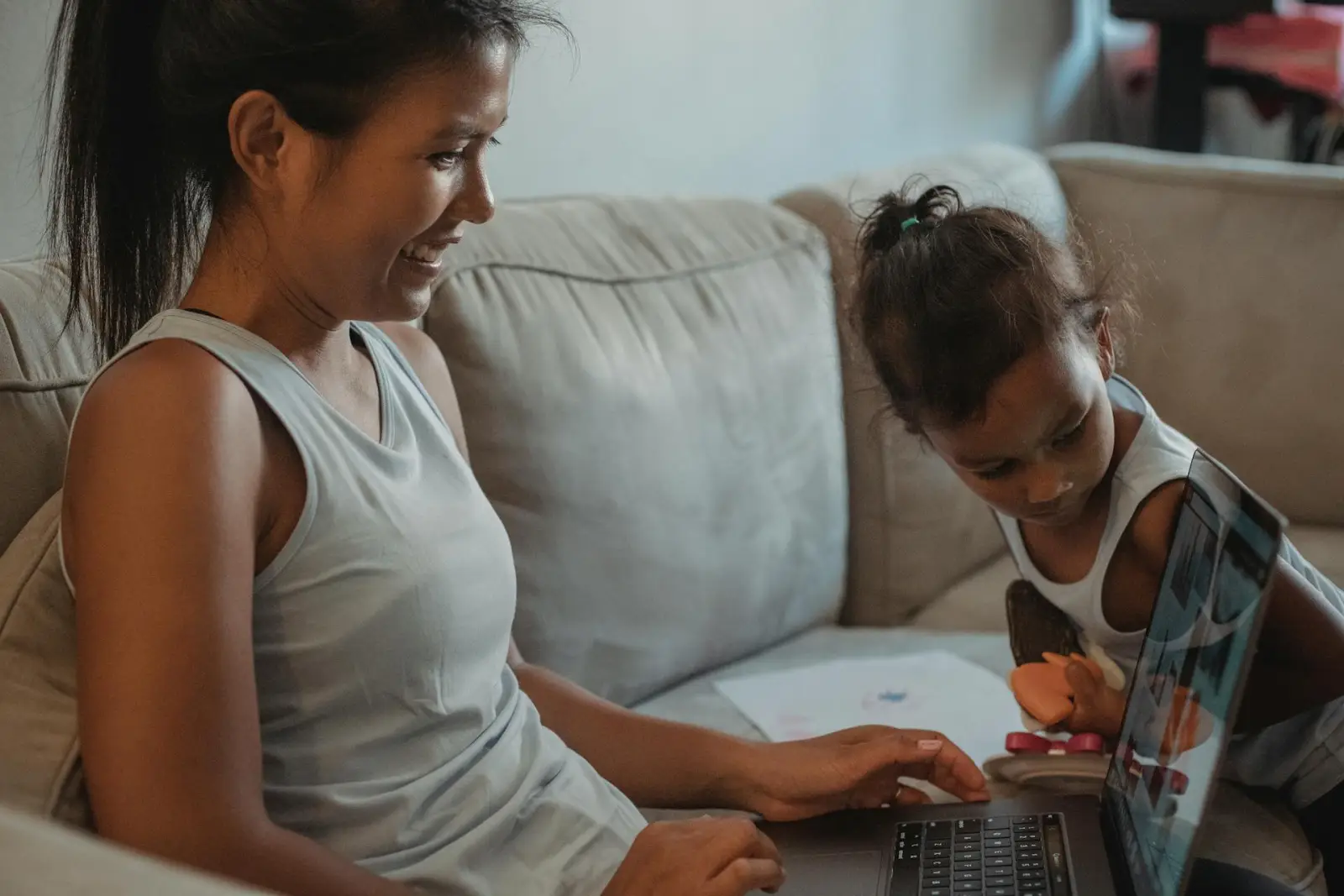 Parent and child looking at a laptop together on a sofa in a living room