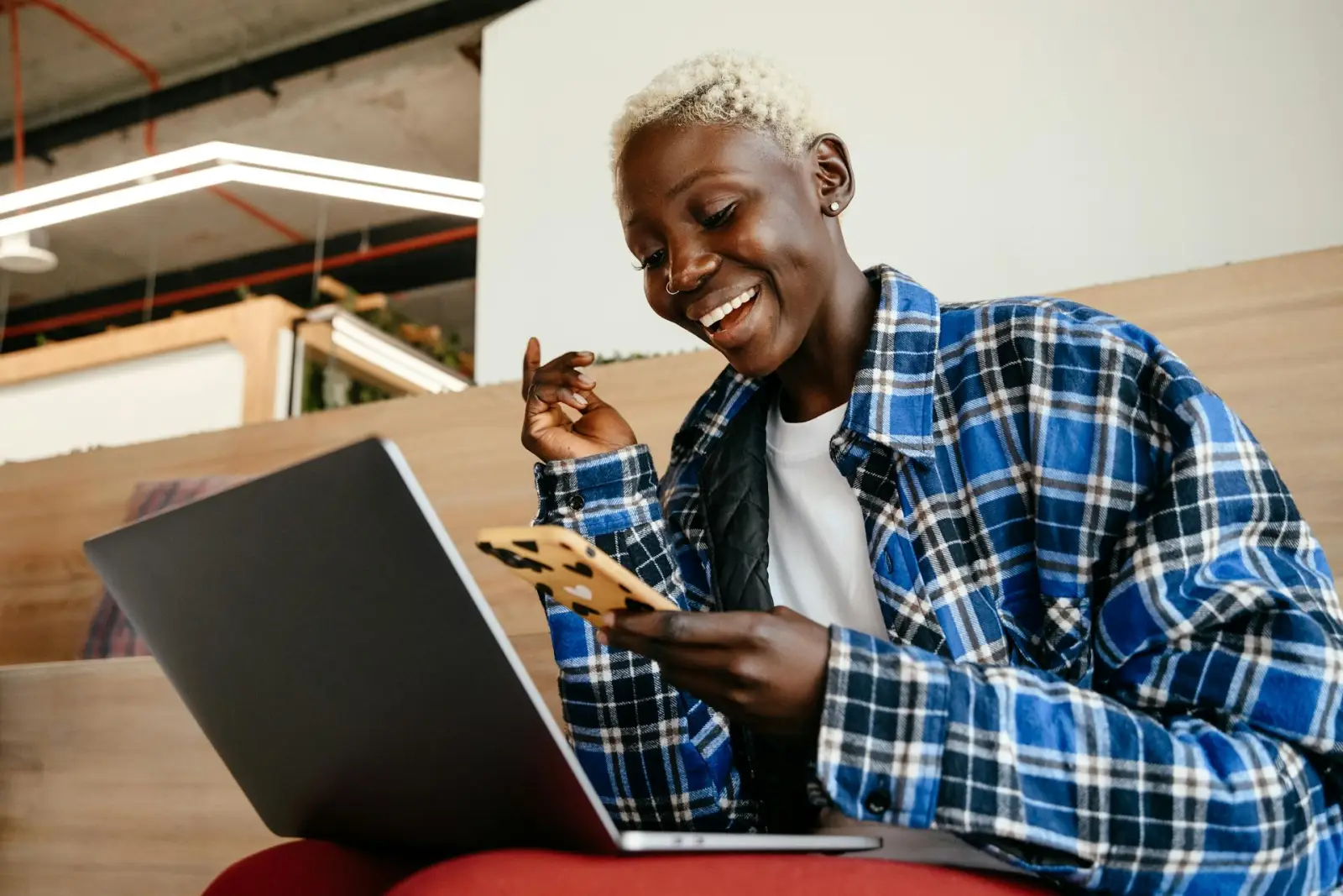 Black professional on phone and laptop reviewing income and household paperwork at home